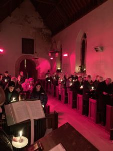 candlelit interior of church ful of people