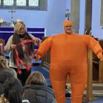 A person dressed as a Christingle and another person helping them