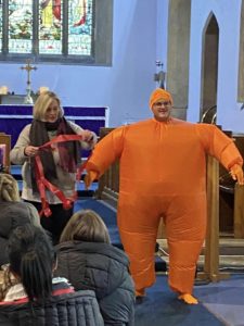 A person dressed as a Christingle and another person helping them